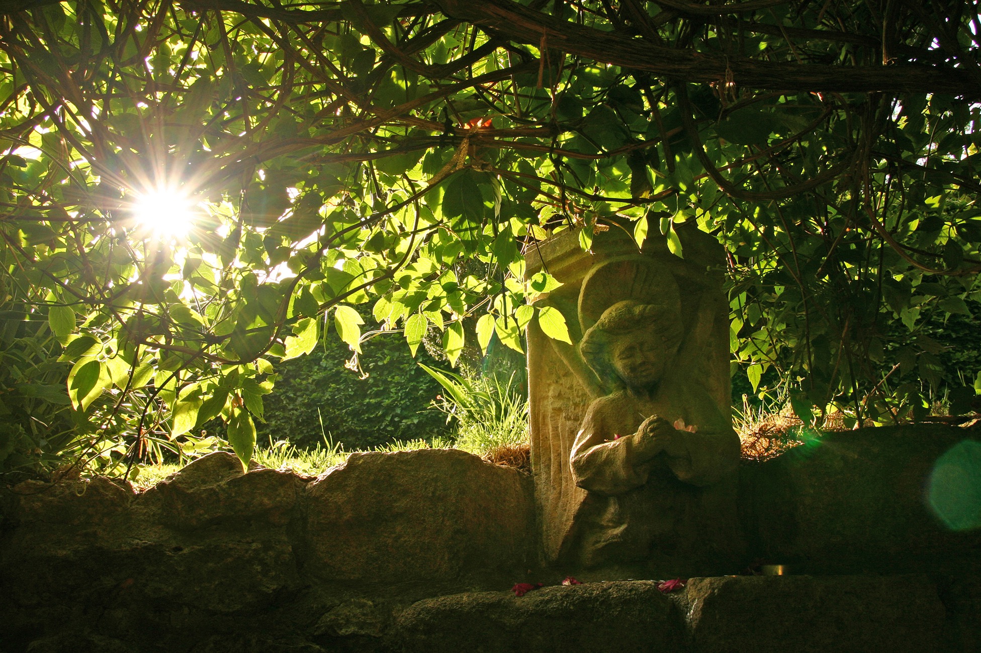Statue unter grünen Blättern im Sonnenlicht